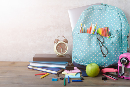 School backpack with coloured pencil and school supplies on brown wood table background back to school concept