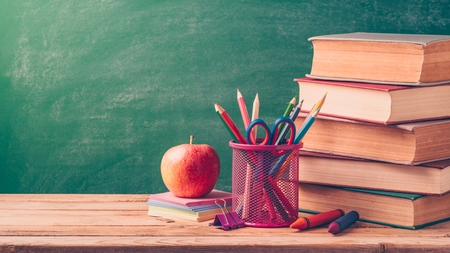 Back to school background with pencils apple and old books over chalkboard