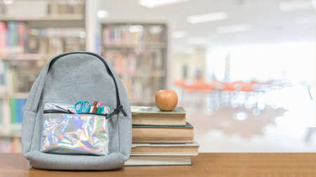 Back to school concept with school books textbooks backpack and stationery supplies on classroom desk with library or class background for educational new academic year begin or study term start