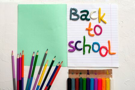 School supplies and inscription back to school colored plasticine letters notebook on a white background multicolored pencils copy space Stock Photo