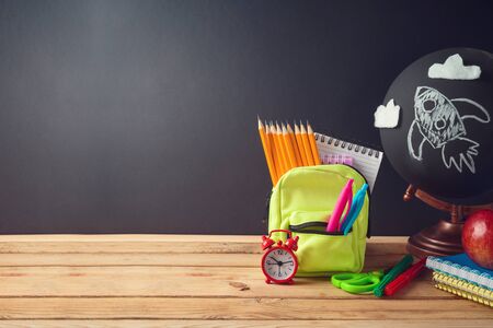 Back to school creative background with small bag backpack and school supplies on wooden table Stock Photo