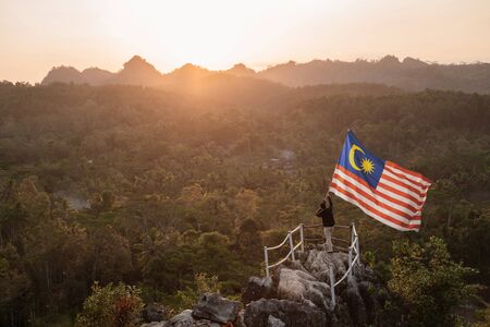 Man with malaysian flag of malaysia on top of the mountain