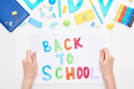 Cropped image of schoolgirl holding card with back to school text isolated on white