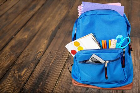 Colorful school supplies in backpack on white background