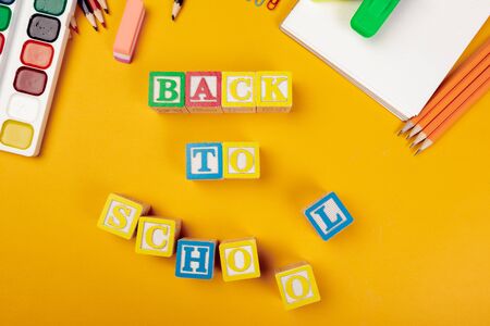 Back to school concept colored wooden alphabetical cubes on bright yellow background creative photo