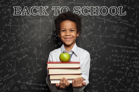 Smiling child in classroom on blackboard background with science formulas