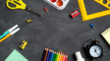 Back to school concept frame of school supplies on a black board background top view flat lay overhead