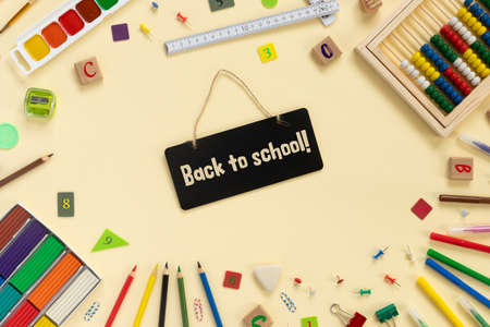 School and office supplies border on beige paper background multicolored pencils paints plasticine abacus pushpins and other school accessories flat lay top view with copy space back to school concept Stock Photo