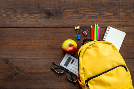 Students supplies in yellow school backpack back to school concept