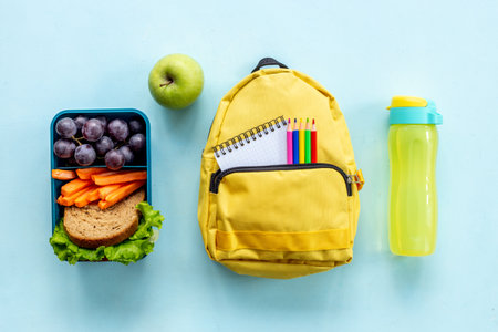 Healthy school lunch box with fruits and backpack top view