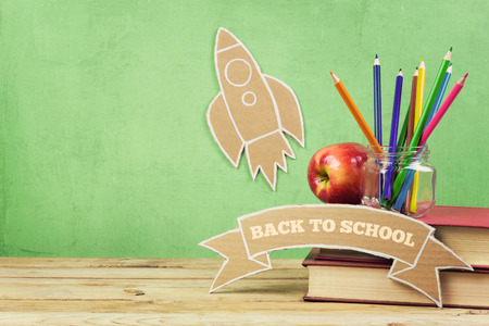 Back to school background with books pencils and cardboard rocket on wooden table