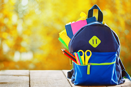 Full school backpack with apple h reautumn nature background Stock Photo