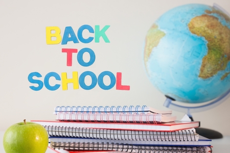 Composite of back to school text with notebooks globe and apple